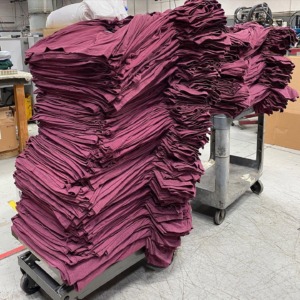 Stacks of maroon shirts in the apparel production facility